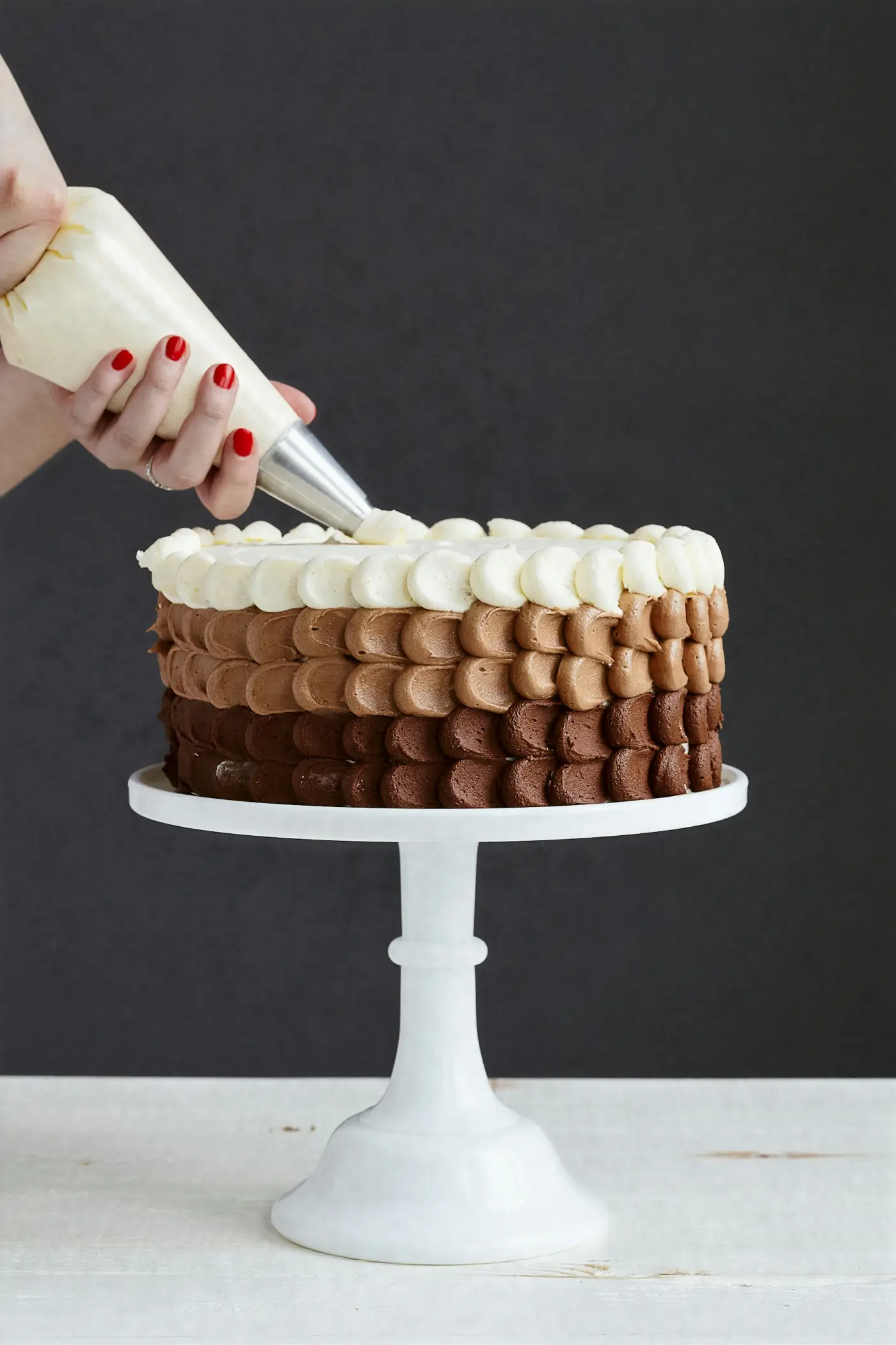 Manos decorando una tarta con manga pastelera